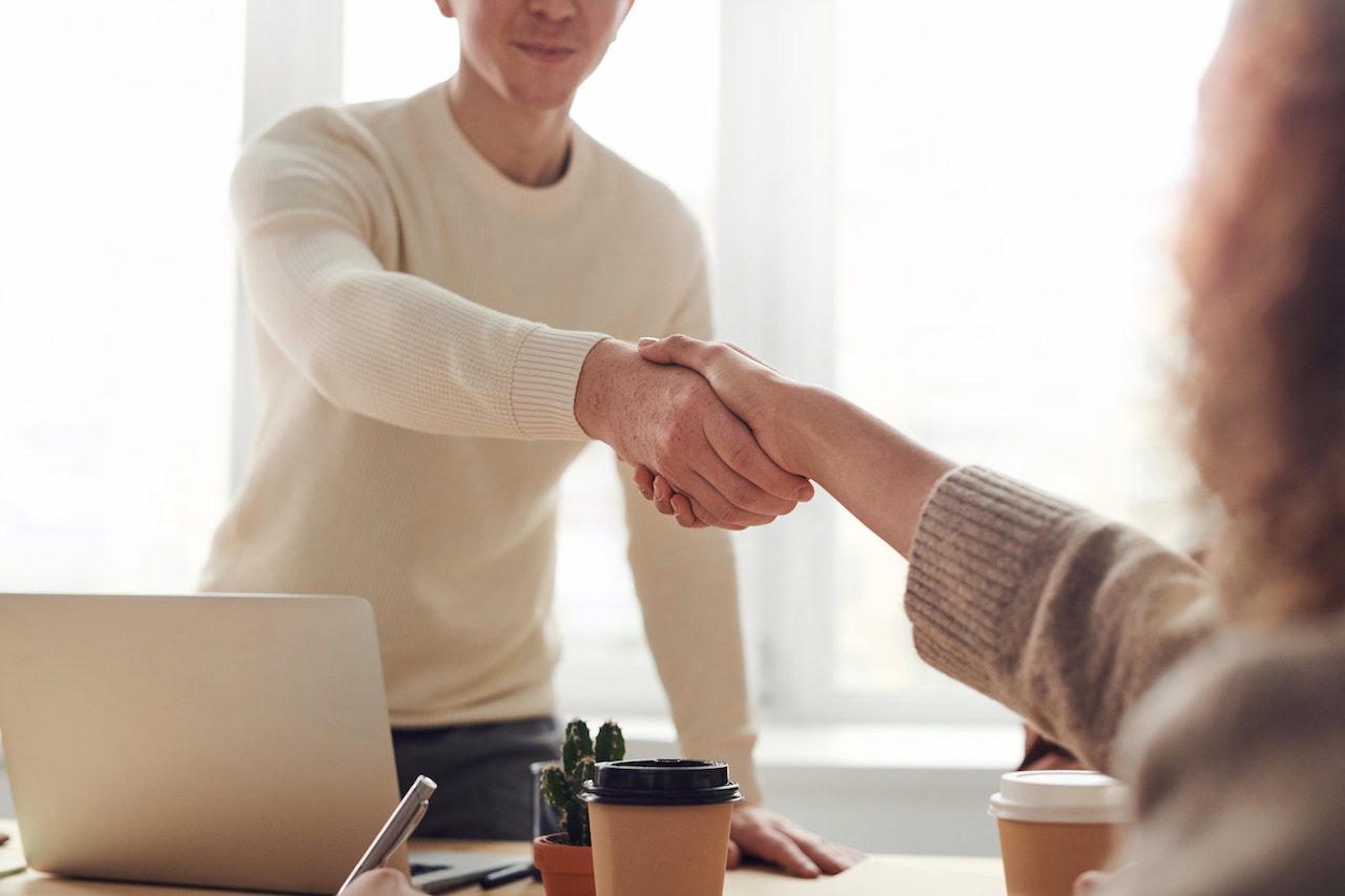 A man reaching out his hand to shake a woman's hand in partnership